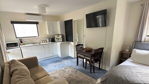 A compact hotel room with a sofa, a bed, a dining table, and a kitchenette. - Country cottage close to airport (pet friendly)  (West Melton)