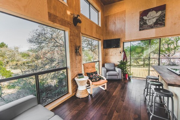 Enjoy expansive views of the surrounding landscape from the large windows in this room, featuring a comfortable seating area and a bar with stools.