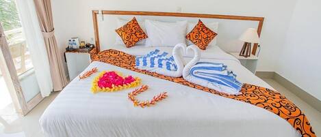 Un letto rifatto con cura, un bouquet floreale a forma di cuore, due asciugamani a forma di cigno e cuscini decorati.