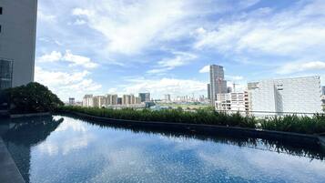 Une piscine sur le toit offrant une vue sur le paysage urbain, entourée de verdure et de bâtiments modernes.