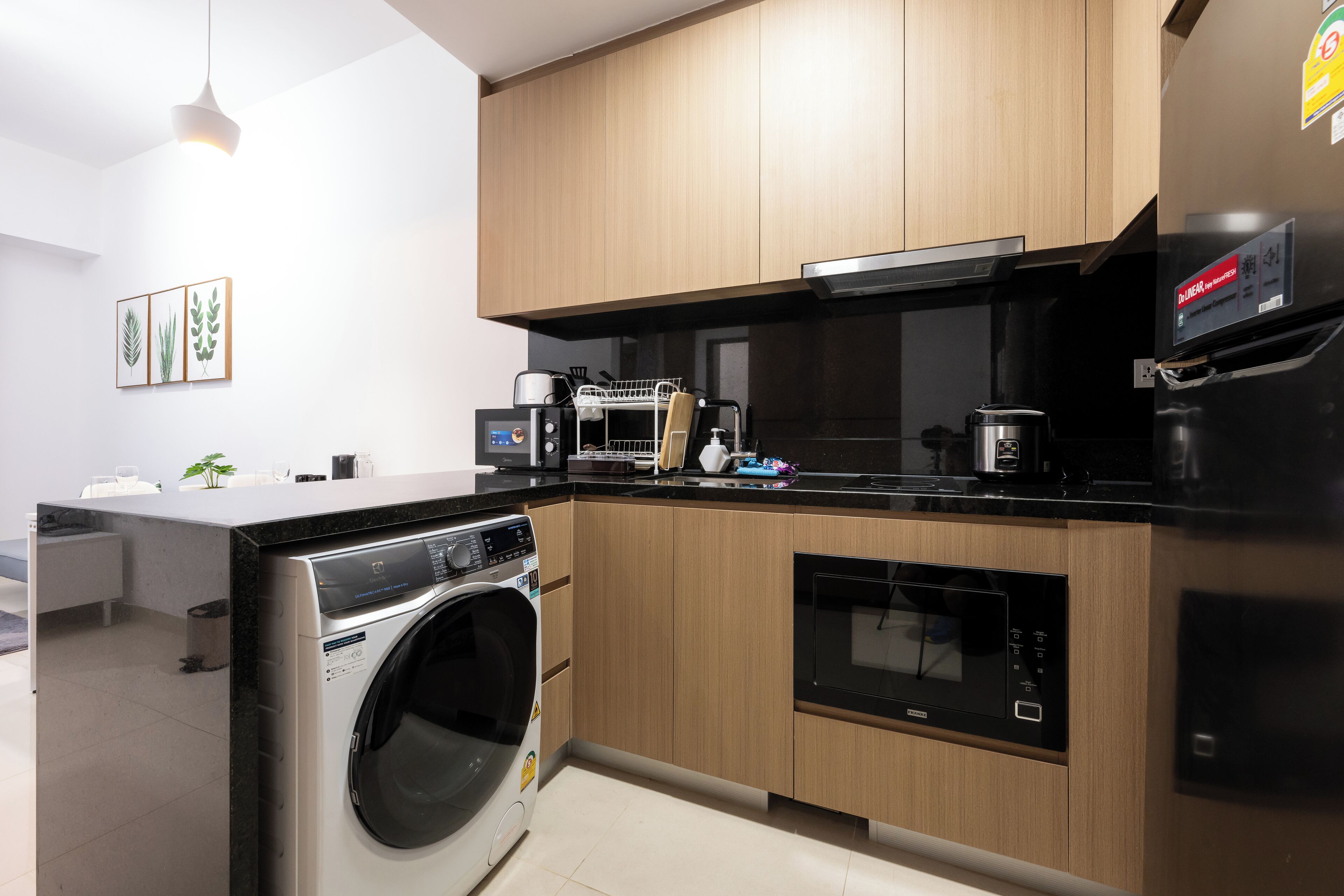 Una cocina moderna con armarios de madera, lavadora integrada, microondas y cafetera.