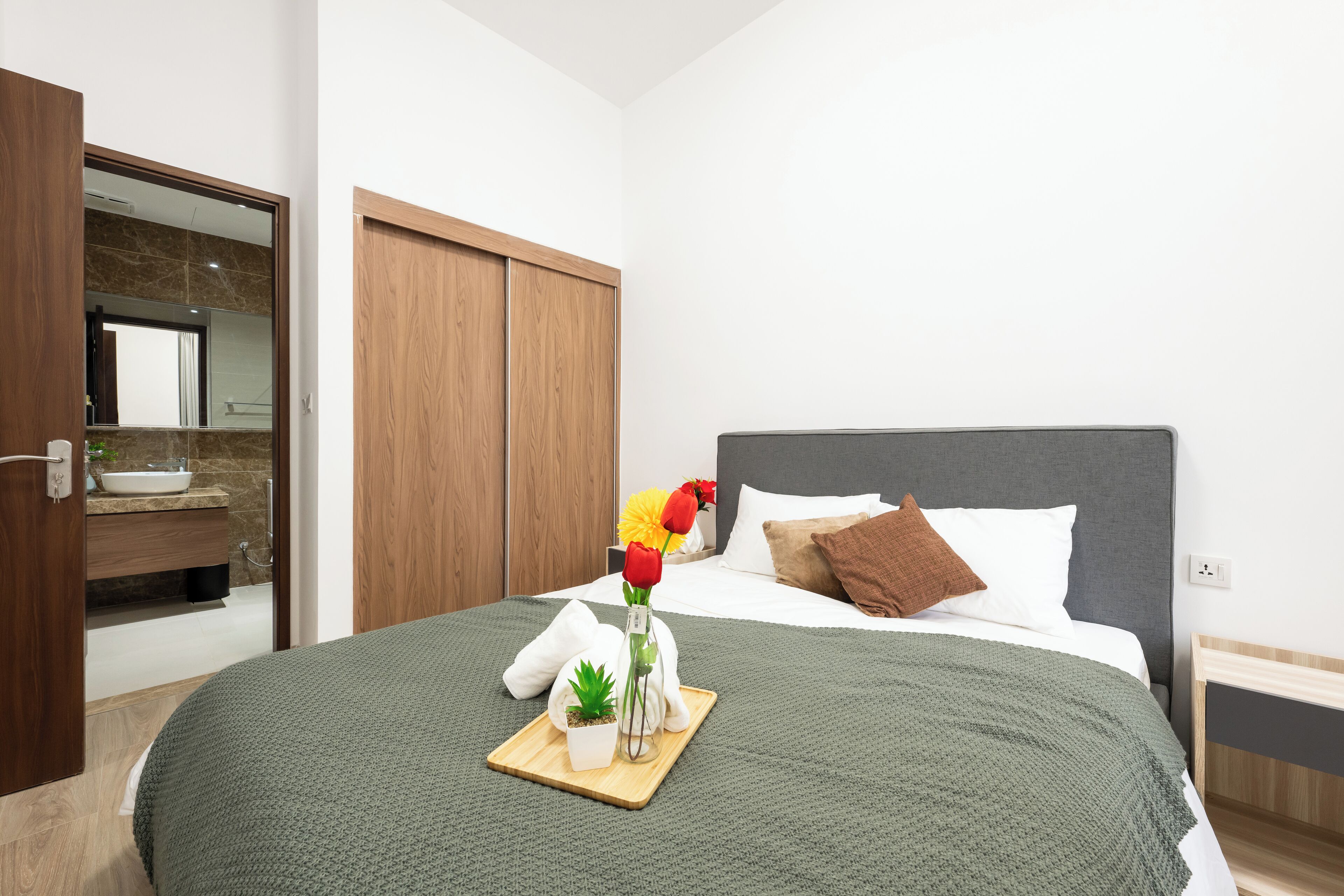A neatly arranged bedroom with a bed, bedside table, and a small bedside plant.