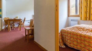 A room with a bed, a desk with chairs, and a window with curtains. - Duplex 3-room, 8 pers, balcony, near slopes (Le Corbier)