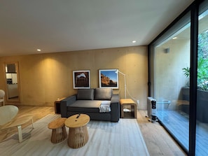A modern living room with a sofa, two wooden stools, a floor lamp, and artwork on the wall. - w* | Alluring 2BR with Balcony in Condesa (Ciudad de México)
