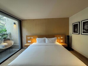 A modern hotel room with a large bed, a view through a glass door, and a wicker chair by the window. - w* | Alluring 2BR with Balcony in Condesa (Ciudad de México)