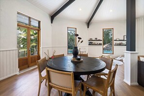 A dining area with a round table, wooden chairs, and a vase with dried flowers. - The Noosa Ranch - Where Nature meets Luxury (Tinbeerwah)