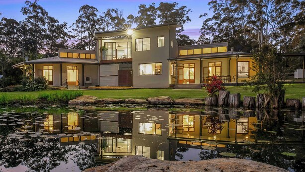 A modern two-story house with a pond in front, large windows, and a well-maintained lawn. - The Noosa Ranch - Where Nature meets Luxury (Tinbeerwah)