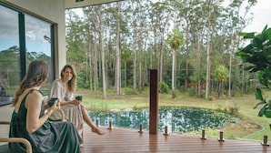 Two people seated on a wooden deck with a view of a pond and trees. - The Noosa Ranch - Where Nature meets Luxury (Tinbeerwah)