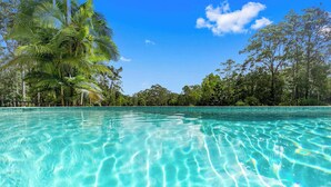 A clear pool with visible water ripples, surrounded by lush green trees and a clear blue sky. - The Noosa Ranch - Where Nature meets Luxury (Tinbeerwah)