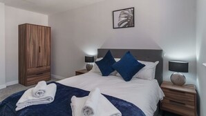 Ein Hotelzimmer mit einem großen Bett, zwei Nachttischen, einem Holzschrank und einem an der Wand befestigten Kunstwerk.