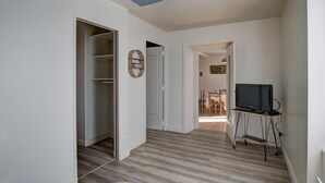 Ein modernes Interieur mit Holzboden, einer Deckenleuchte und einem Fernseher auf einem Standfuß.
