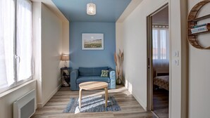 Ein modernes Wohnzimmer mit blauer Akzentwand, einem Holztisch, einer Couch und einer Pendelleuchte.