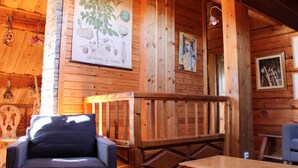 A wooden interior with a wooden bench, a table, and a wall-mounted poster.