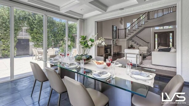 A spacious dining area with a glass table, surrounded by chairs, and a view of the outdoors.