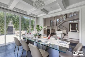 Un vaste espace dédié à la salle à manger, avec une table en verre entourée de chaises, et une vue sur l’extérieur.