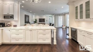 A spacious kitchen with white cabinetry, a marble island, and a built-in oven.
