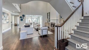 A spacious living area with a modern staircase, a fireplace, and a view of the outdoors.