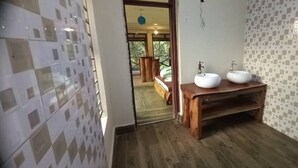 Een badkamer met een houten wastafelmeubel, twee wastafels en uitzicht op een balkon met een bed.
