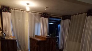 Een hotelkamer met een bed, een houten bureau en uitzicht door een raam met gordijnen.