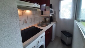 Eine kleine Küche mit Mikrowelle, Spüle und Waschmaschine.