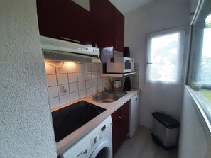 A compact kitchen with a microwave, sink, and washing machine.