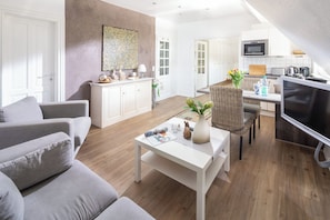 Un salon moderne avec un canapé, une table basse et un coin repas agrémenté d’une chaise en osier.