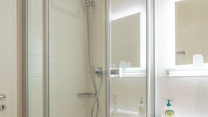 A modern bathroom with a glass-enclosed shower, a white sink, and a mirror above the sink. - LIEBENEY - BEACH CHAIR // (Norderney)