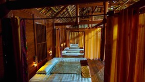 A corridor with wooden walls and ceiling, leading to a series of beds with pillows and blankets. - MUONG PHANG HOMESTAY (Muong Phang)