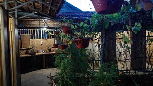 A rustic garden with hanging terracotta pots, a bamboo fence, and a thatched roof structure. - MUONG PHANG HOMESTAY (Muong Phang)
