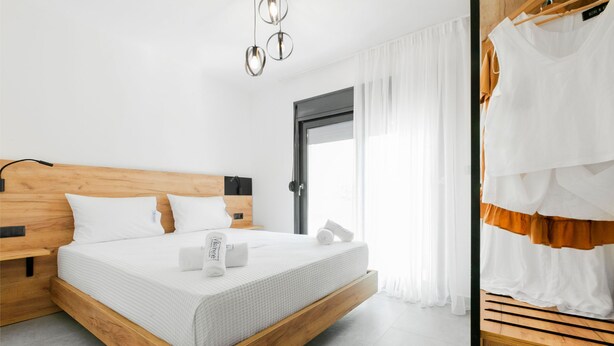 Un dormitorio moderno con cabecera de cama de madera, ropa de cama blanca y una mesita de noche.
