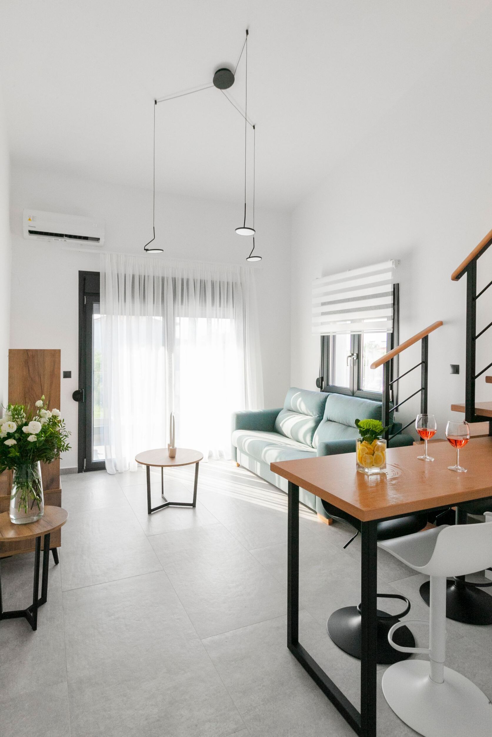 Una sala moderna con un sofá, una mesa de comedor y una escalera.