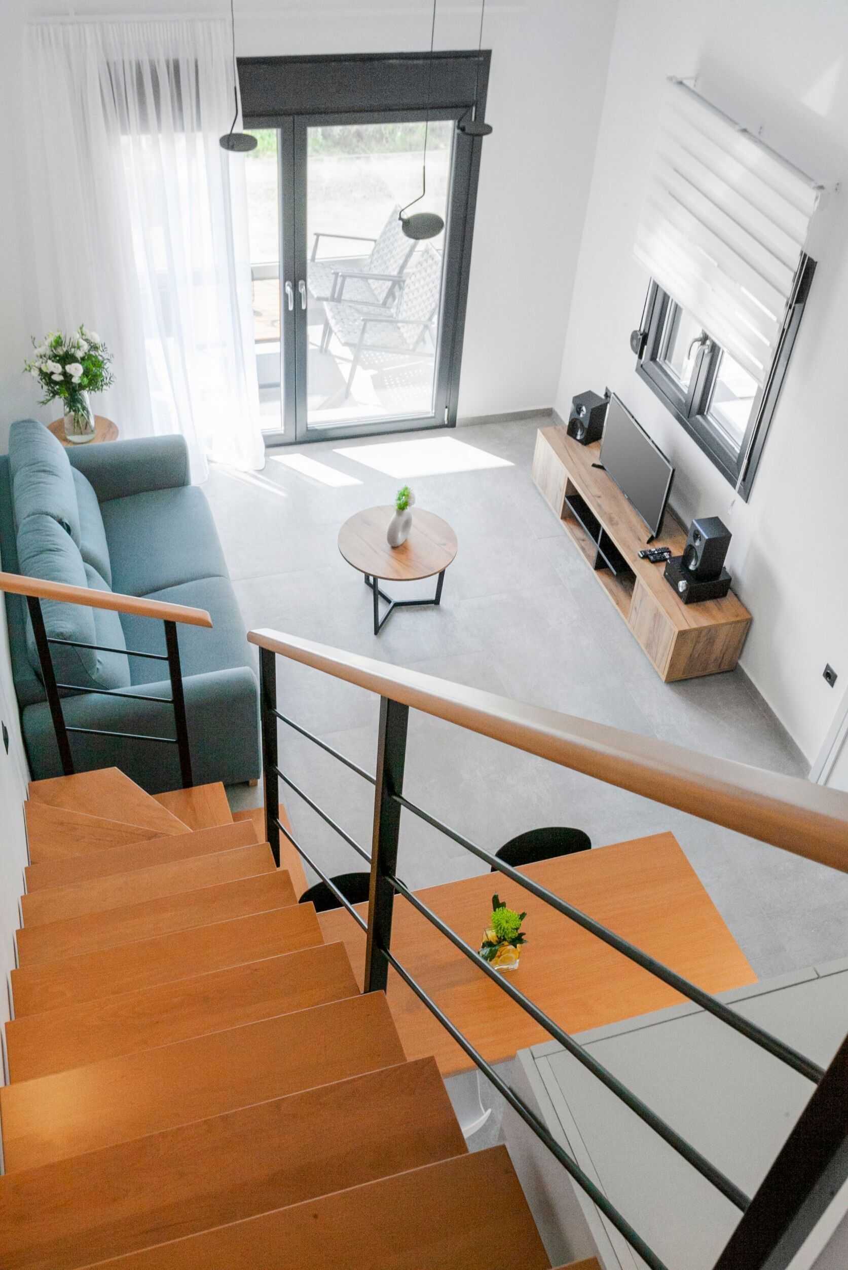 Een moderne woonkamer met een trap, een bank, een salontafel en een televisie.