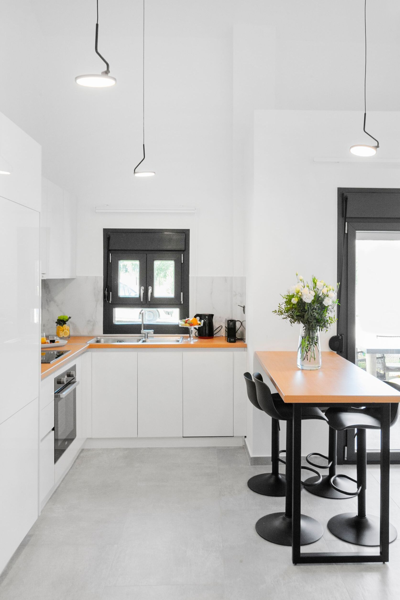 A modern kitchen with white cabinets, a wooden countertop, and a dining area with a table and chairs.