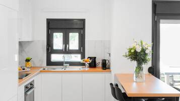A modern kitchen with white cabinets, a wooden countertop, and a dining area with a table and chairs.