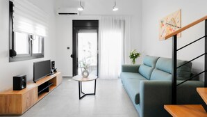 Una sala moderna con televisor de pantalla plana, mueble de entretenimiento de madera, sofá azul claro y una pequeña mesa redonda.
