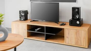 Un mueble moderno de entretenimiento con un televisor de pantalla plana, dos altavoces y un control remoto.