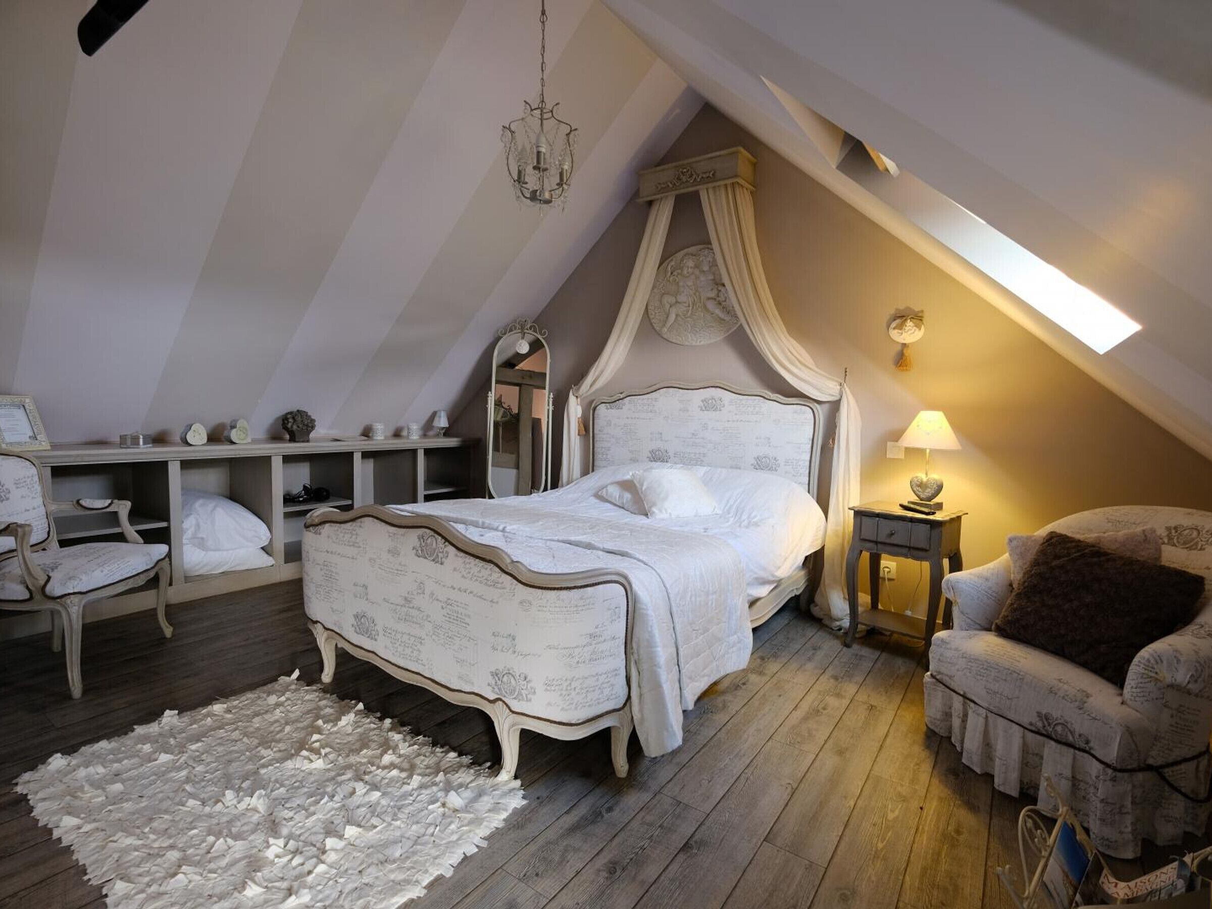 Ein Schlafzimmer mit einem Himmelbett, Holzboden, einem weißen Teppich, einem Nachttisch mit Lampe und einem Sessel.