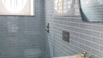 A bathroom with a white toilet, a sink with a mirror, and a shower.