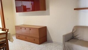 A room with a wooden cabinet, a sofa, and a dining table with chairs. - Cecchi Mansion (Nardò)