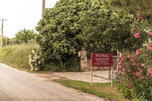 A sign for a property named "POYRAZ BAGAVELERİ" with contact information. - Poyraz Bağ Evleri (Bozcaada)