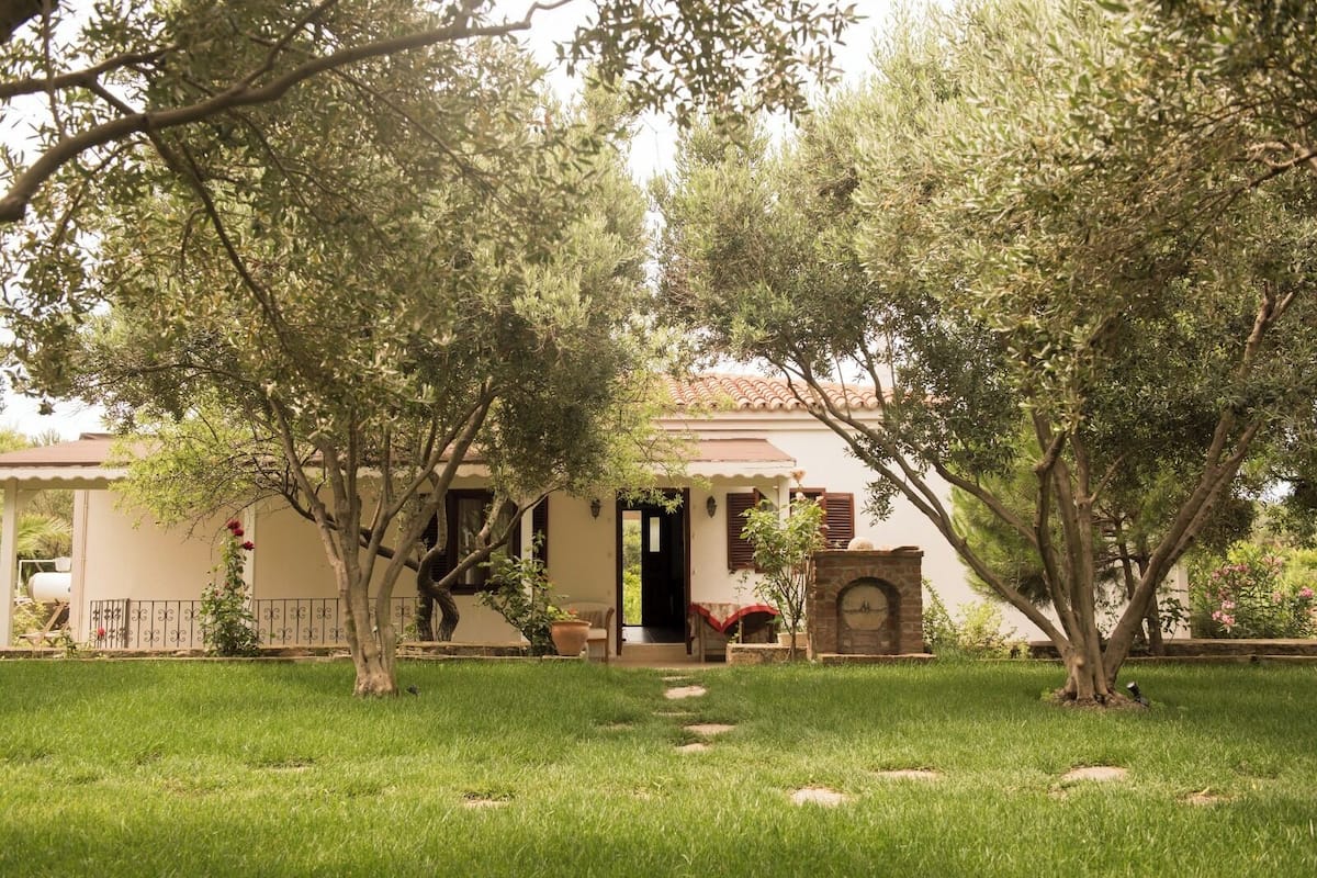 A house with a tiled roof, a brick oven, and a well-maintained lawn with stepping stones.