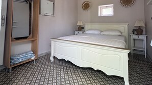 Un dormitorio con cama, armario, espejo, lámpara colgante y suelo estampado.