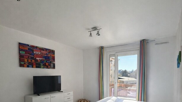 A bedroom with a bed, a TV, a dresser, and a window with curtains. - T1 bis Proche Centre-ville, Campagne et Commodités (Rodez)