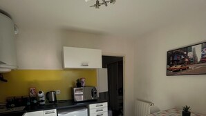 A compact kitchen with a dining area, a ceiling fan, and a view of the street through an open door. - T1 bis Proche Centre-ville, Campagne et Commodités (Rodez)