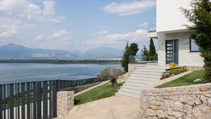 A modern house with a stone staircase leading to a balcony overlooking a lake and mountains. - The Luxury Villa by PikHost (Shkodër)