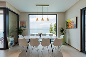 A modern dining room with a large table, four chairs, and pendant lights. - The Luxury Villa by PikHost (Shkodër)