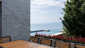 A wooden deck with benches overlooking a pool and ocean view. - The Luxury Villa by PikHost (Shkodër)