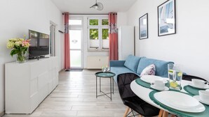 Un salon moderne avec un téléviseur, un canapé et une table à manger, ainsi que des assiettes et des tasses.