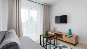 Habitación de hotel moderna con cama, una mesita, televisor y vistas al exterior.