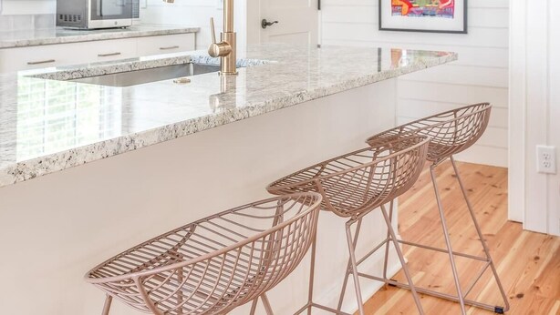 Una cocina moderna con una isla grande, taburetes de bar y una lámpara colgante.